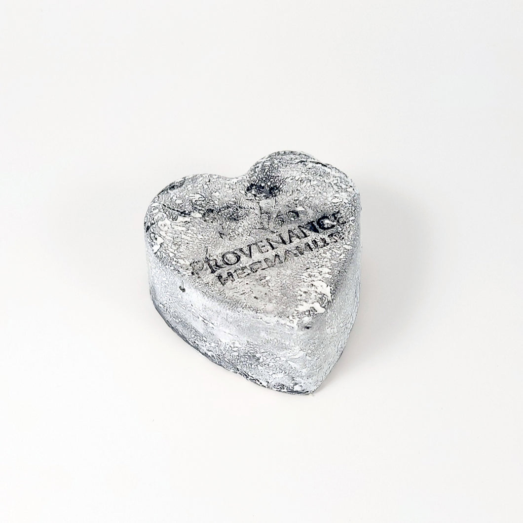Handmade charcoal, heart-shaped soap bar with light coating of white powder.