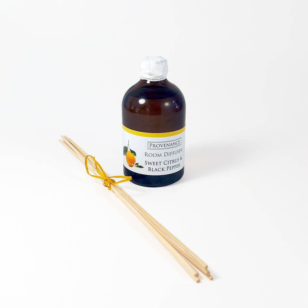 Diffuser oil in amber glass bottle with cork stopper and diffuser sticks tied with a colorful bow.