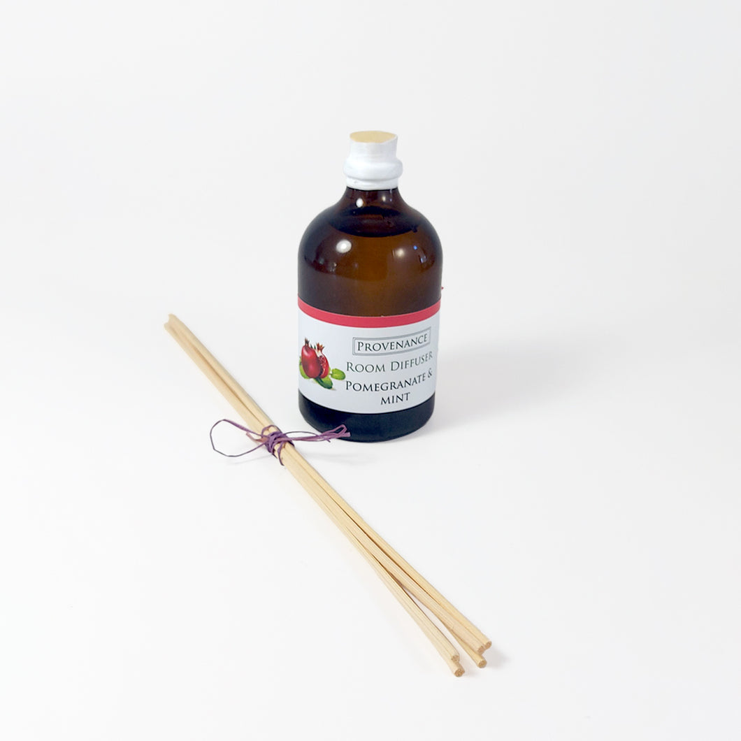 Diffuser oil in amber glass bottle with cork stopper and diffuser sticks tied with a colorful bow.
